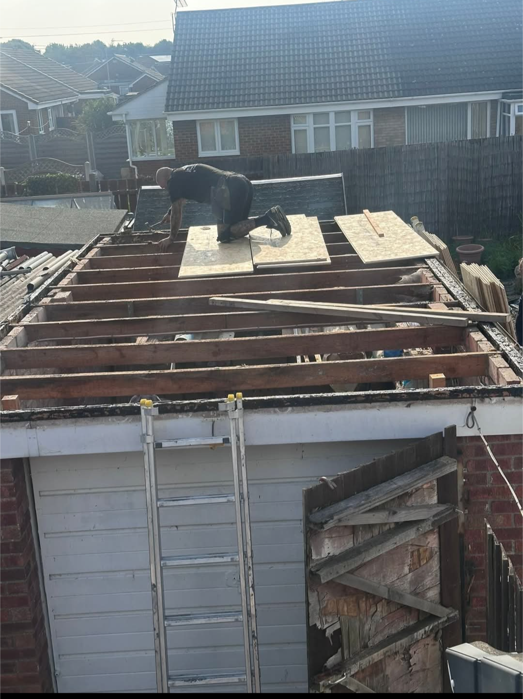 Garage roof stripped back to exposed timber joists during roofing work.